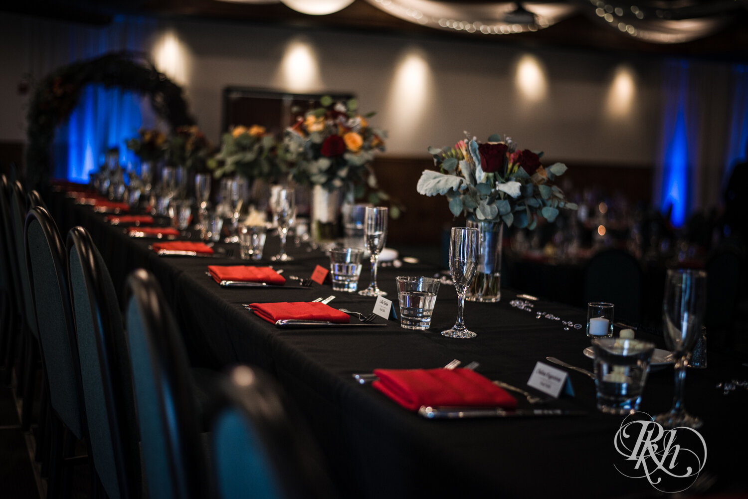 Indoor wedding reception setup with black tablecloth and red accents at Rockwoods in Otsego, Minnesota.