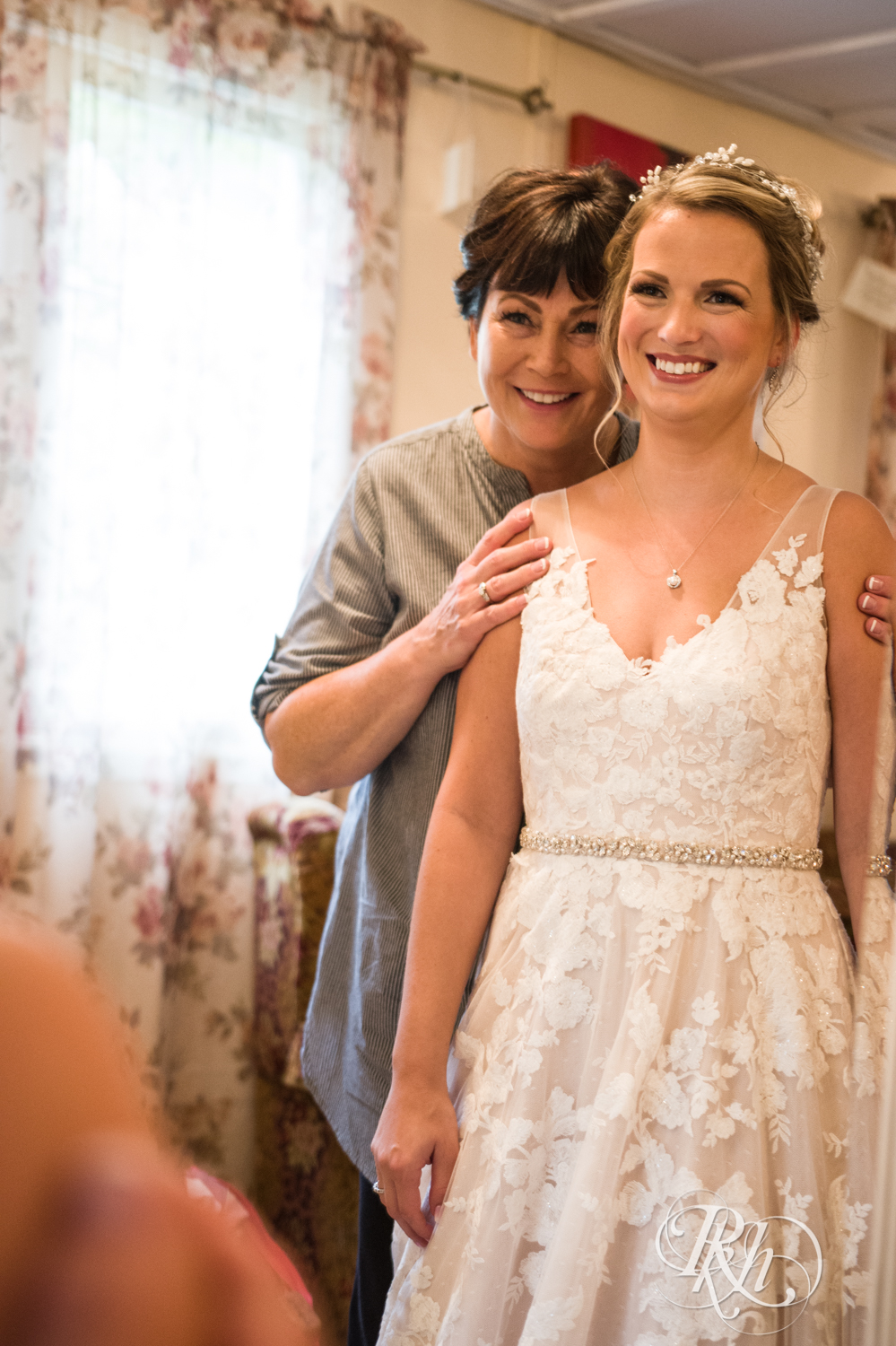 Bride getting zipped into dress by mom before wedding at Camrose Hill Flower Farm in Stillwater, Minnesota.