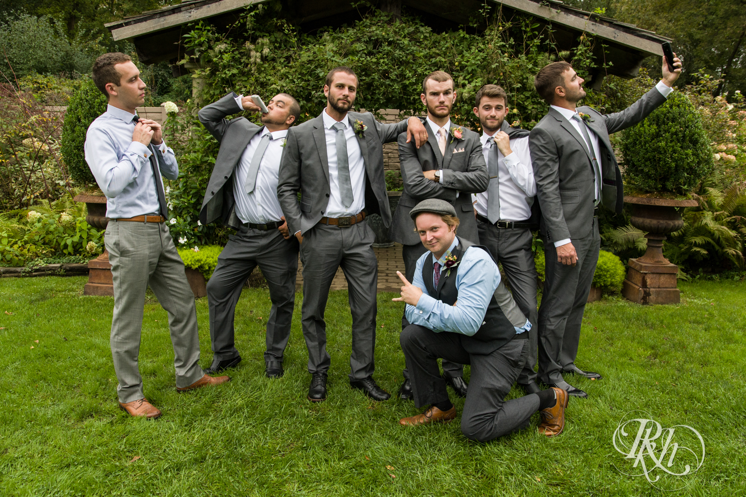 Wedding party in grey suits laugh in the rain at Camrose Hill in Stillwater, Minnesota.