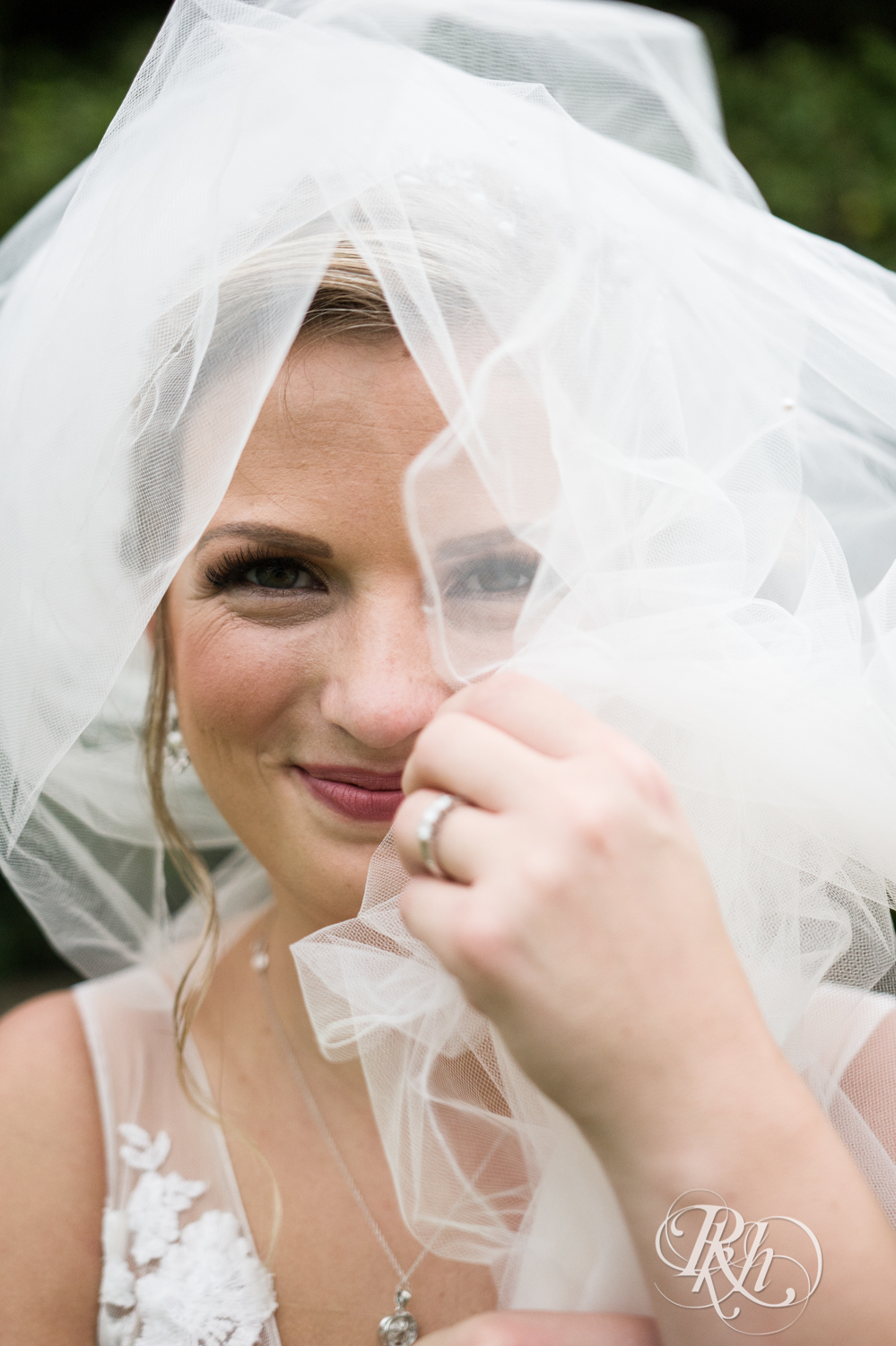 Bride smiles in veil on rainy day at Camrose Hill in Stillwater, Minnesota.