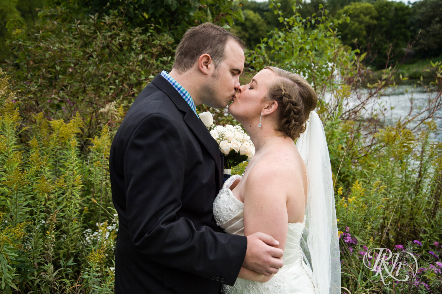 Bride and groom kiss by wildflowers at Eagan Community Center in Eagan, Minnesota.