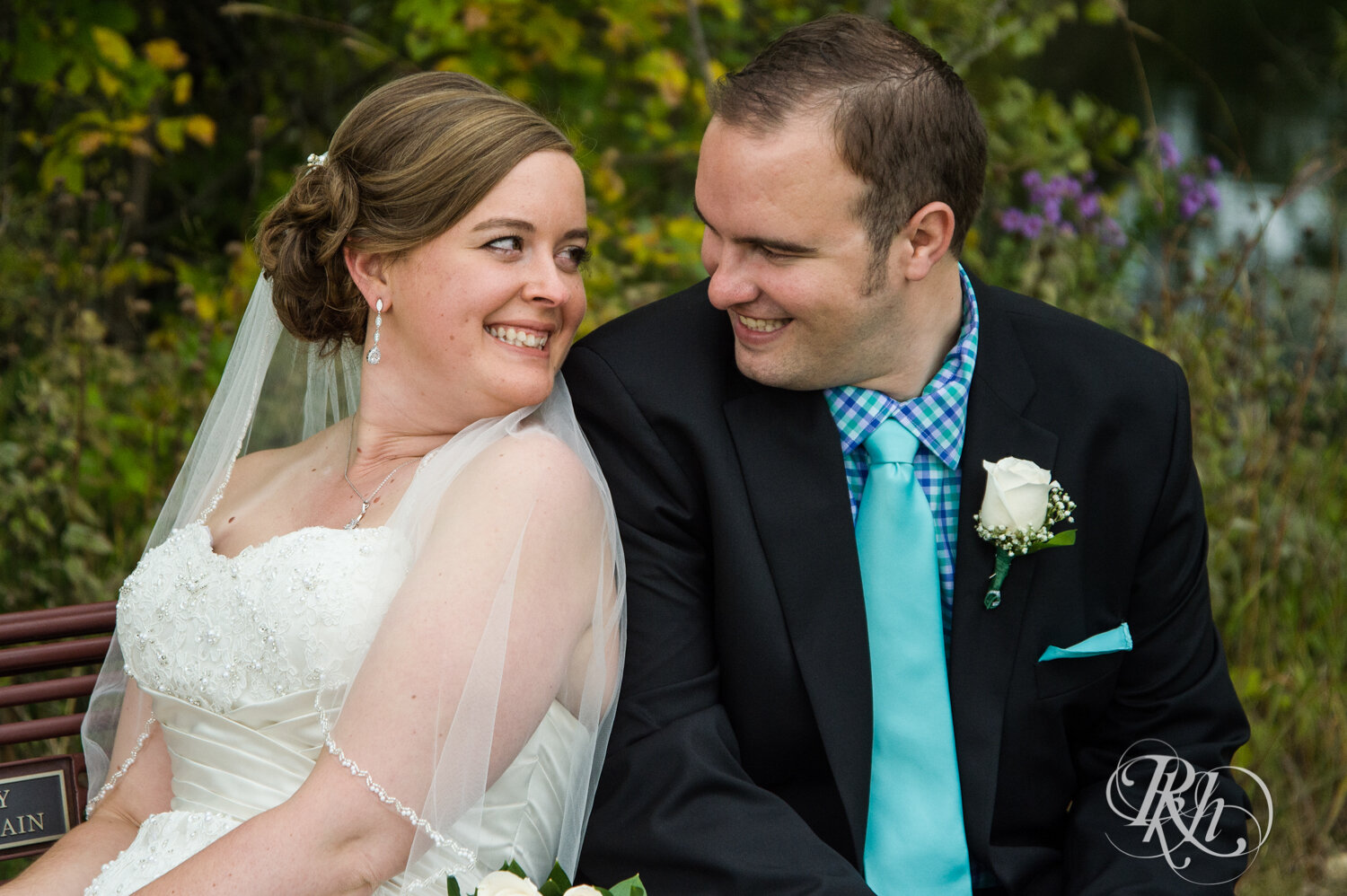 Bride and groom smile by wildflowers at Eagan Community Center in Eagan, Minnesota.