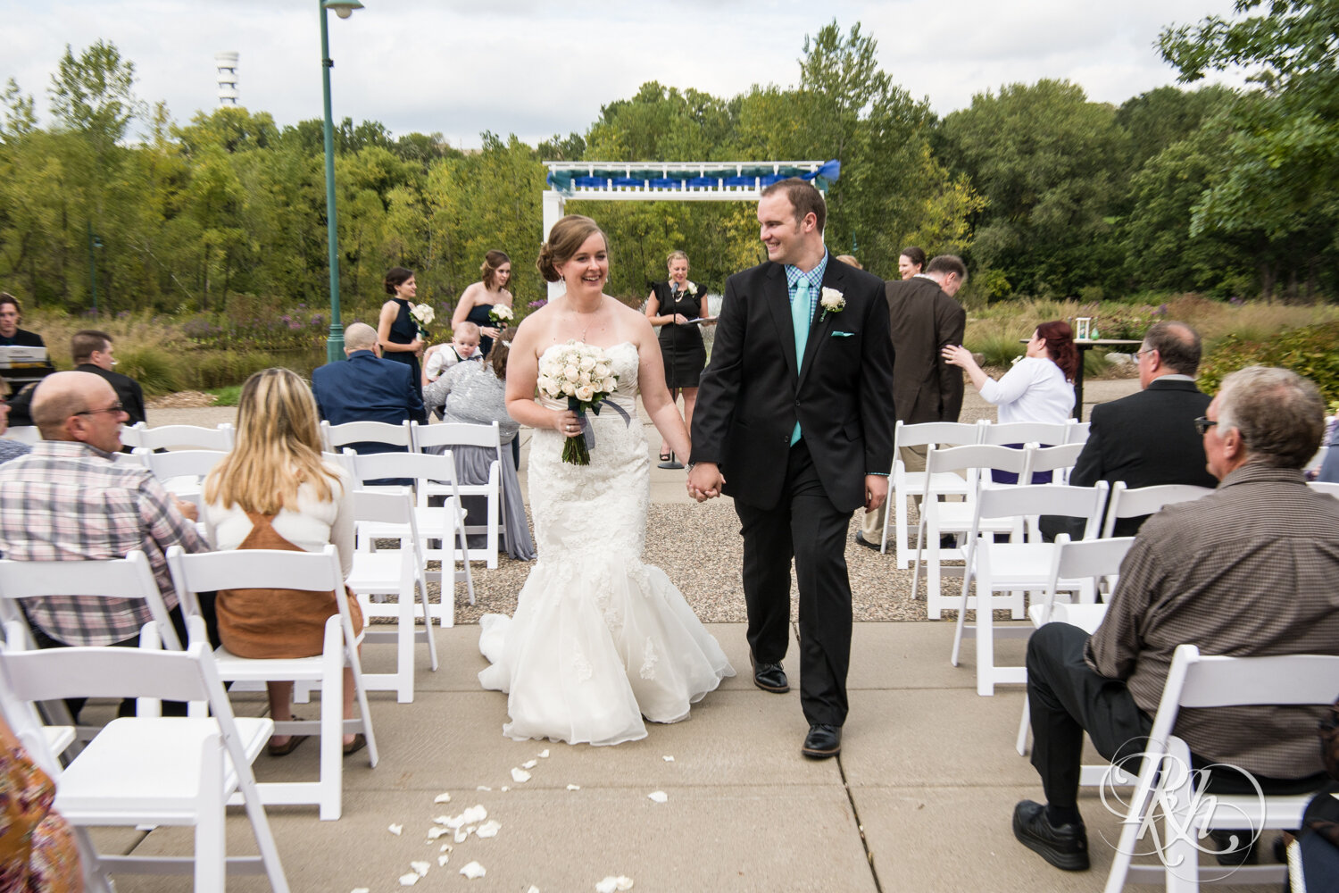 Bride and groom walk at outdoor wedding ceremony at Eagan Community Center in Eagan, Minnesota.