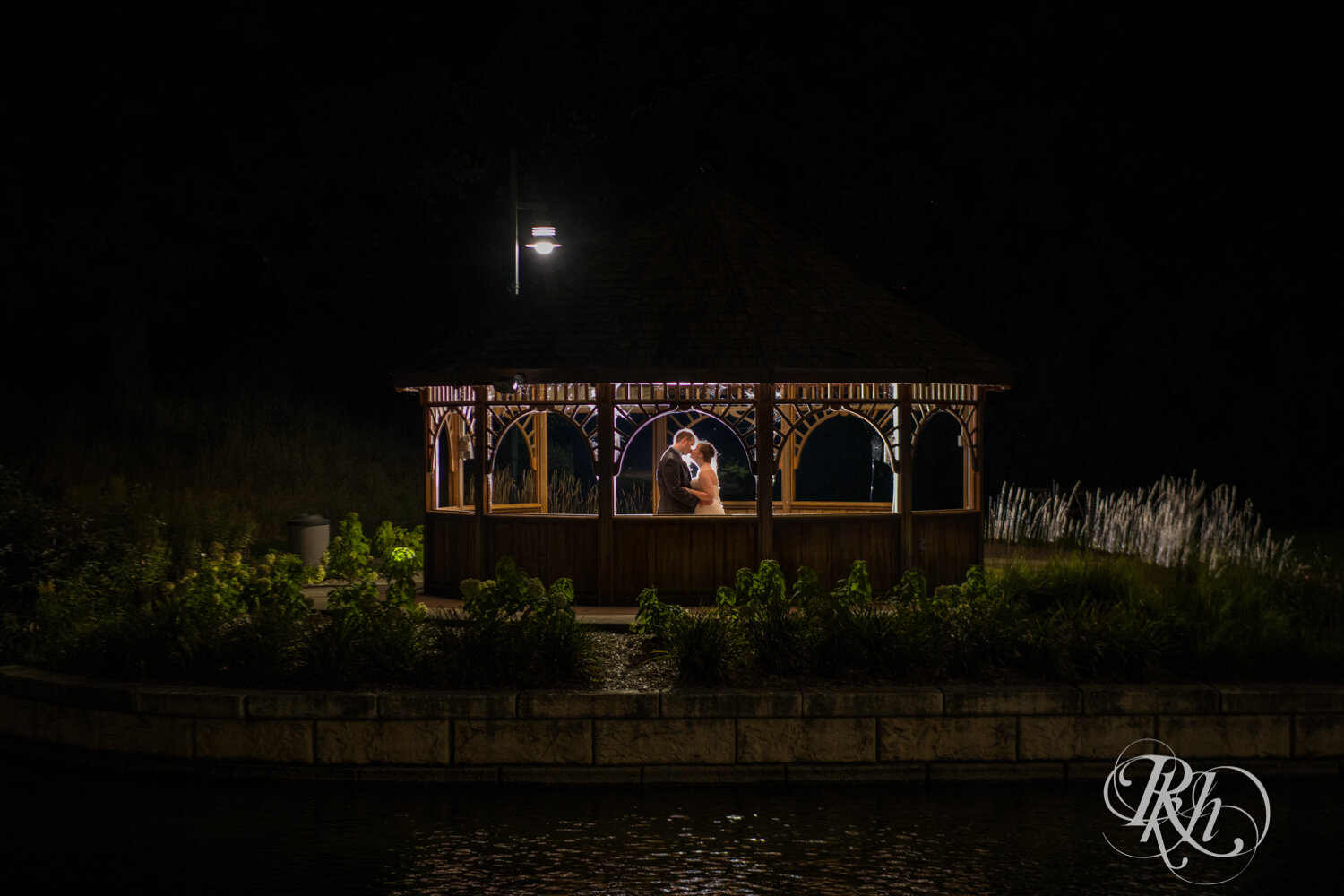 Bride and groom kiss in a gazebo at night at Eagan Community Center in Eagan, Minnesota.