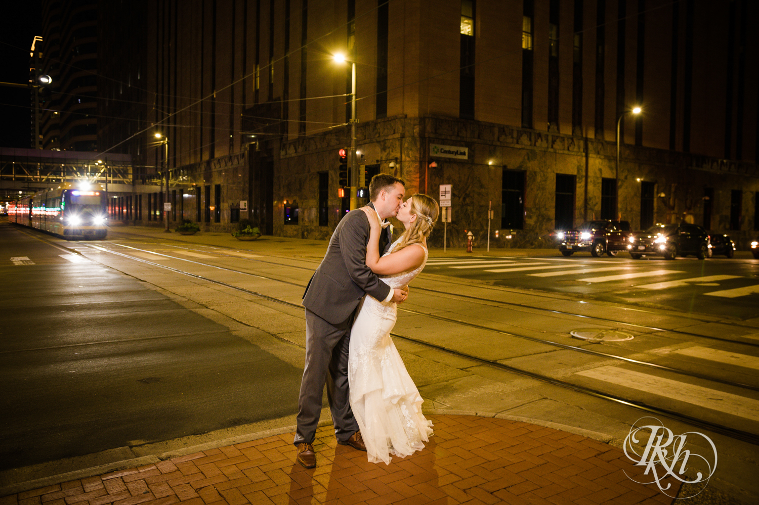 Bride and groom kiss at night in front of the Light Rail in Minneapolis, Minnesota.