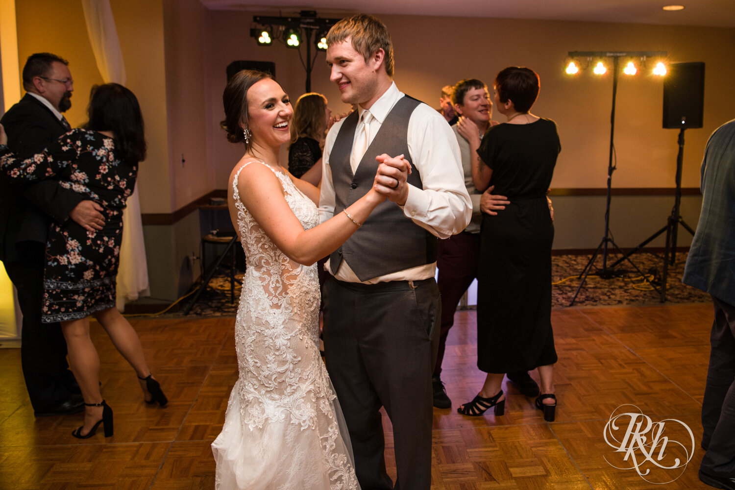 Bride and groom dance with guests at wedding reception on rainy day at The Wilds Golf Club in Prior Lake, Minnesota.