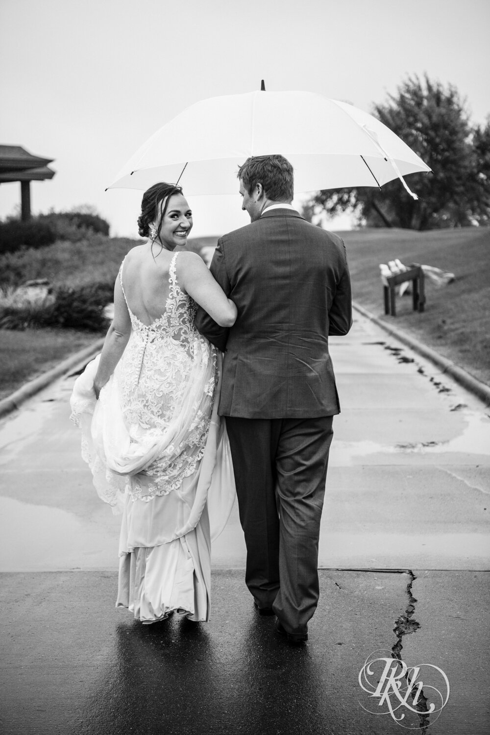 Bride and groom walking under umbrella on rainy day