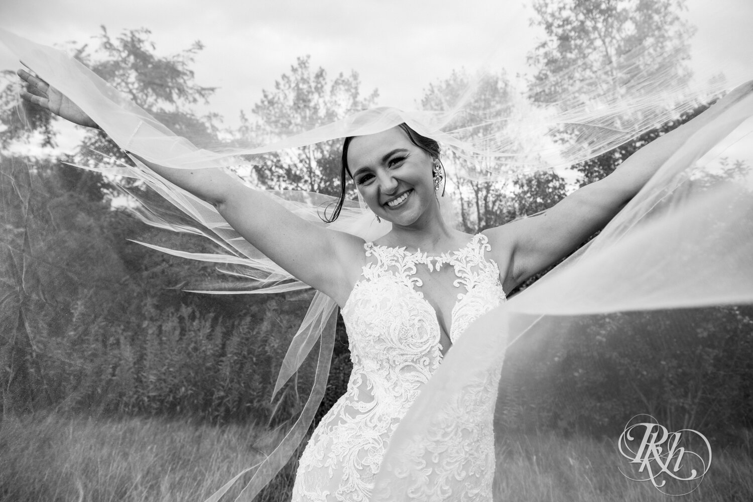 Bride smiles under long veil on rainy day at The Wilds Golf Club in Prior Lake, Minnesota.