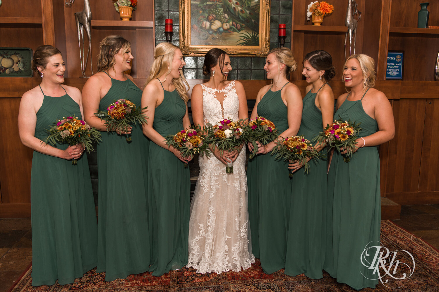 Wedding party in green dresses and gray suits smile on rainy day at The Wilds Golf Club in Prior Lake, Minnesota.