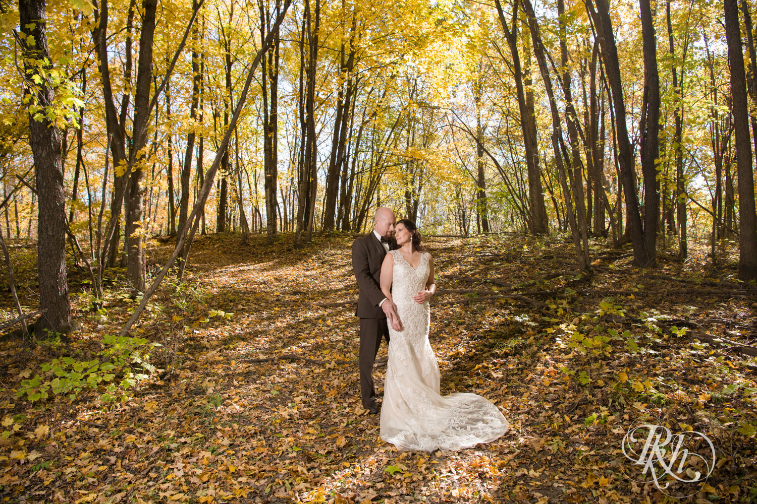 Bride and groom hold hands in woods at Minnesota Horse and Hunt Club in Prior Lake, Minnesota.