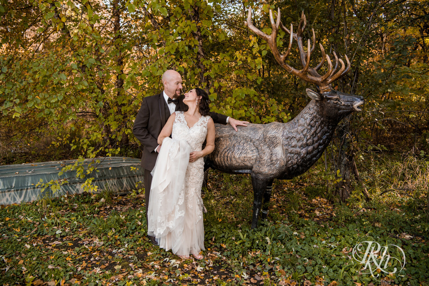 Bride and groom smile in front of deer at Minnesota Horse and Hunt Club in Prior Lake, Minnesota.