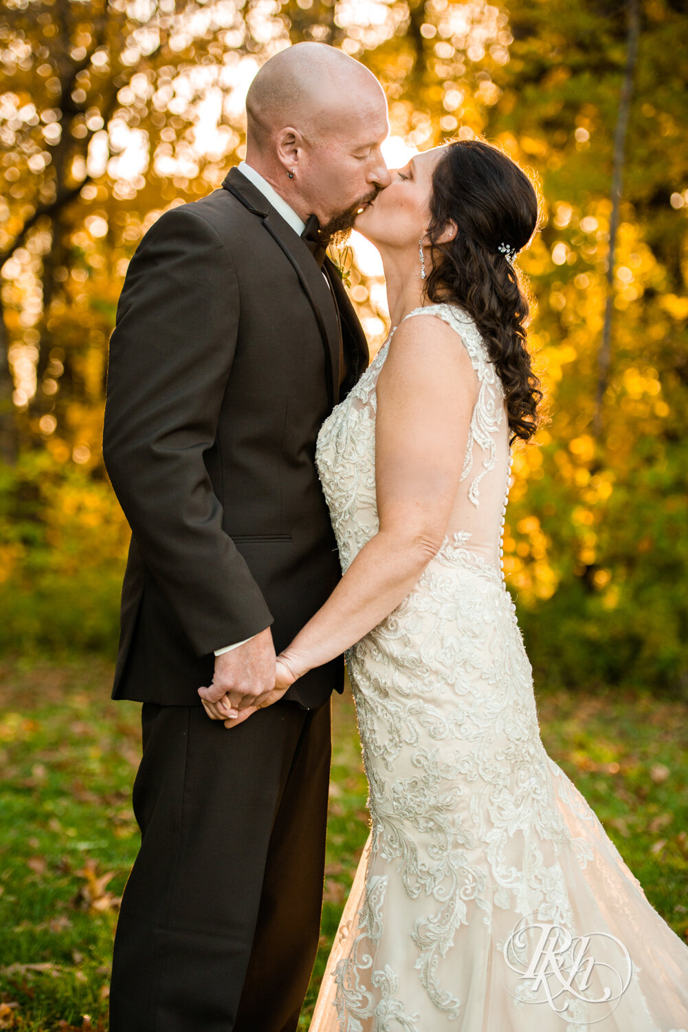 Bride and groom kiss in woods with fall colors at Minnesota Horse and Hunt Club in Prior Lake, Minnesota.