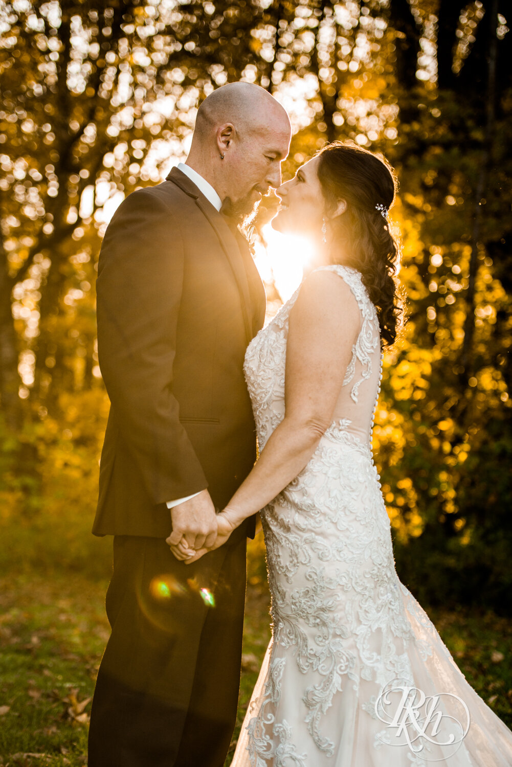 Bride and groom kiss in woods with fall colors at sunset at Minnesota Horse and Hunt Club in Prior Lake, Minnesota.