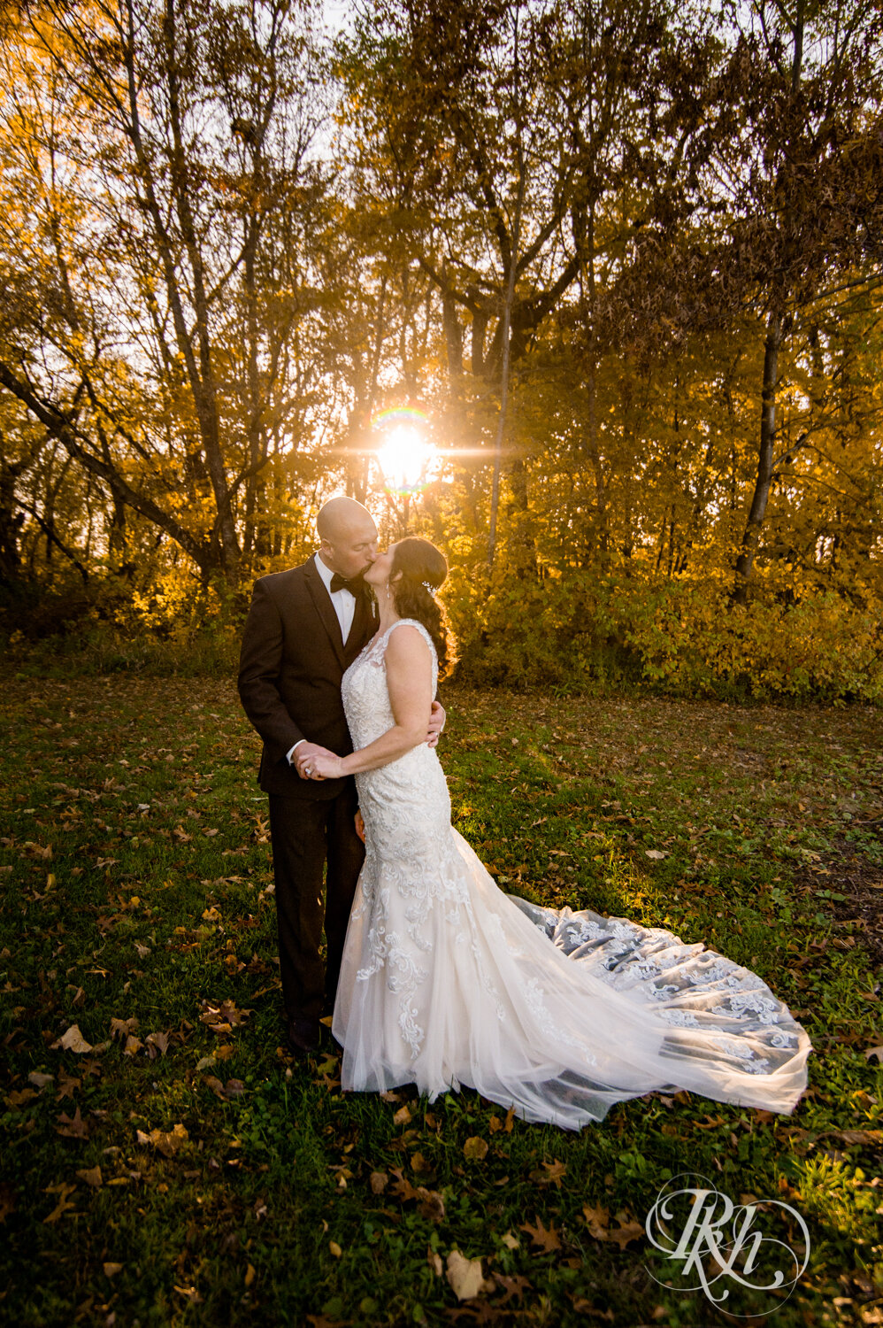 Bride and groom kiss in woods with fall colors at sunset at Minnesota Horse and Hunt Club in Prior Lake, Minnesota.