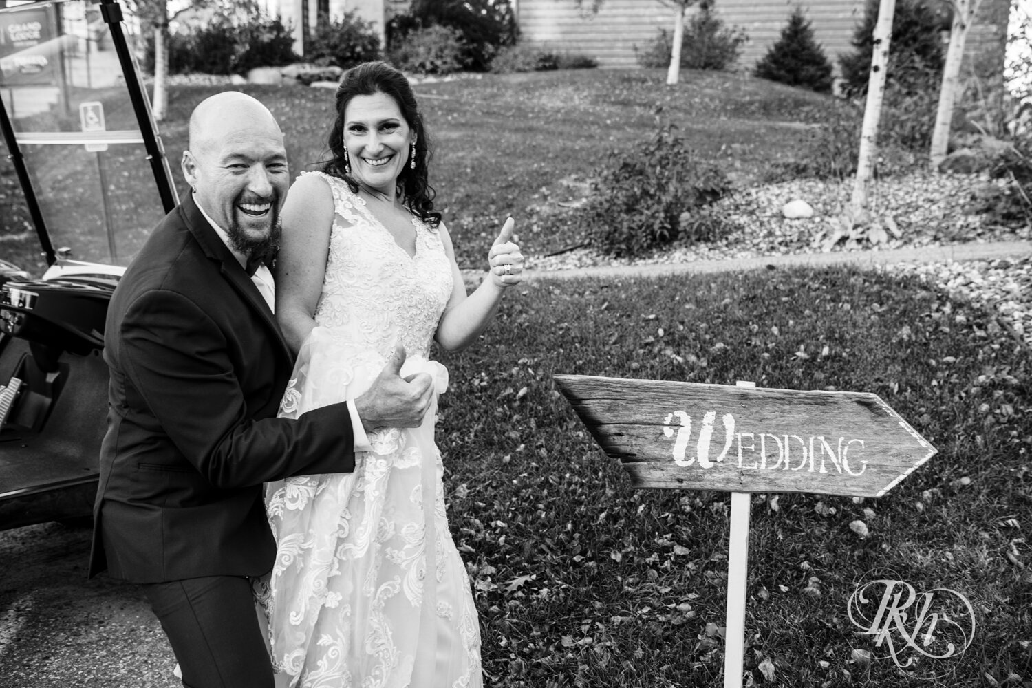 Bride and groom smile by wedding sign at Minnesota Horse and Hunt Club in Prior Lake, Minnesota.