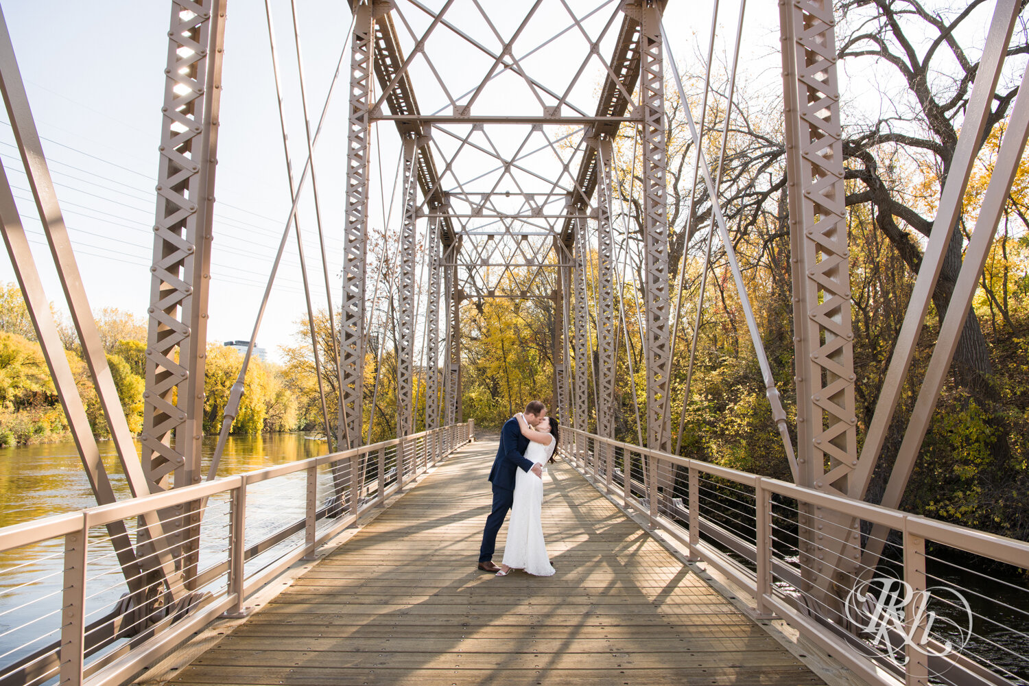 Bride and groom kiss on bridge on Boom Island in Minneapolis, Minnesota.