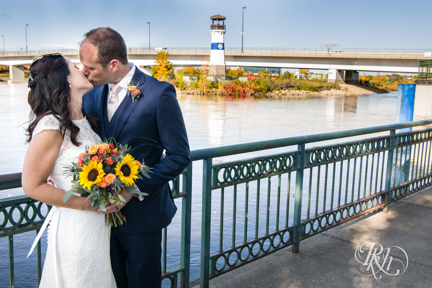 Bride and groom kiss with flowers and lighthouse