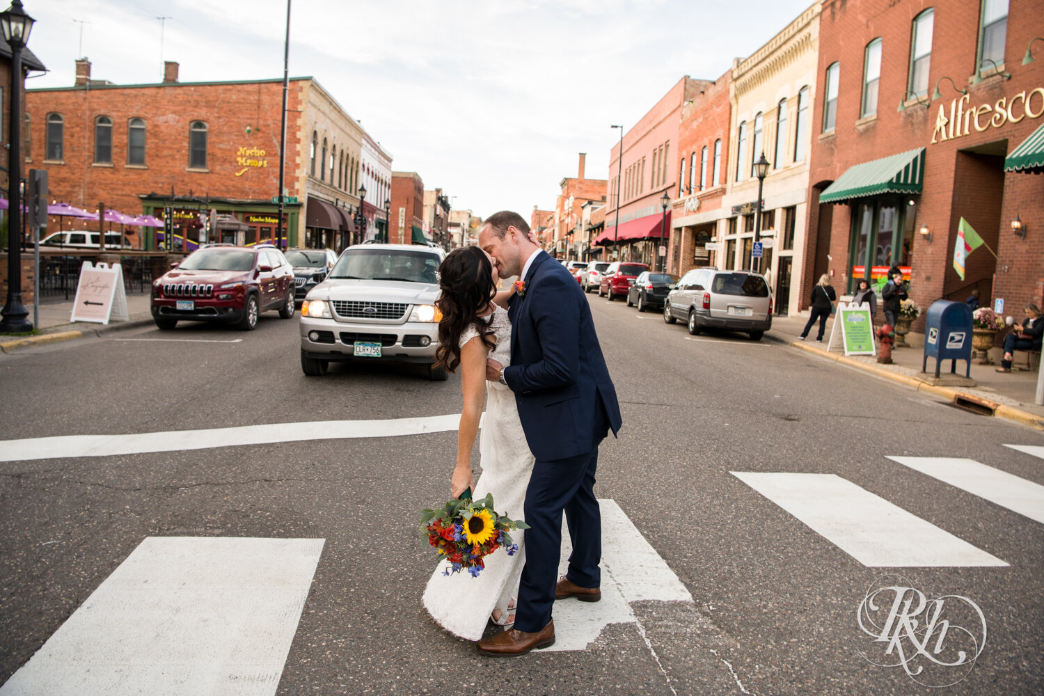 Bride and groom kiss in the street in Stillwater, Minnesota at sunset.