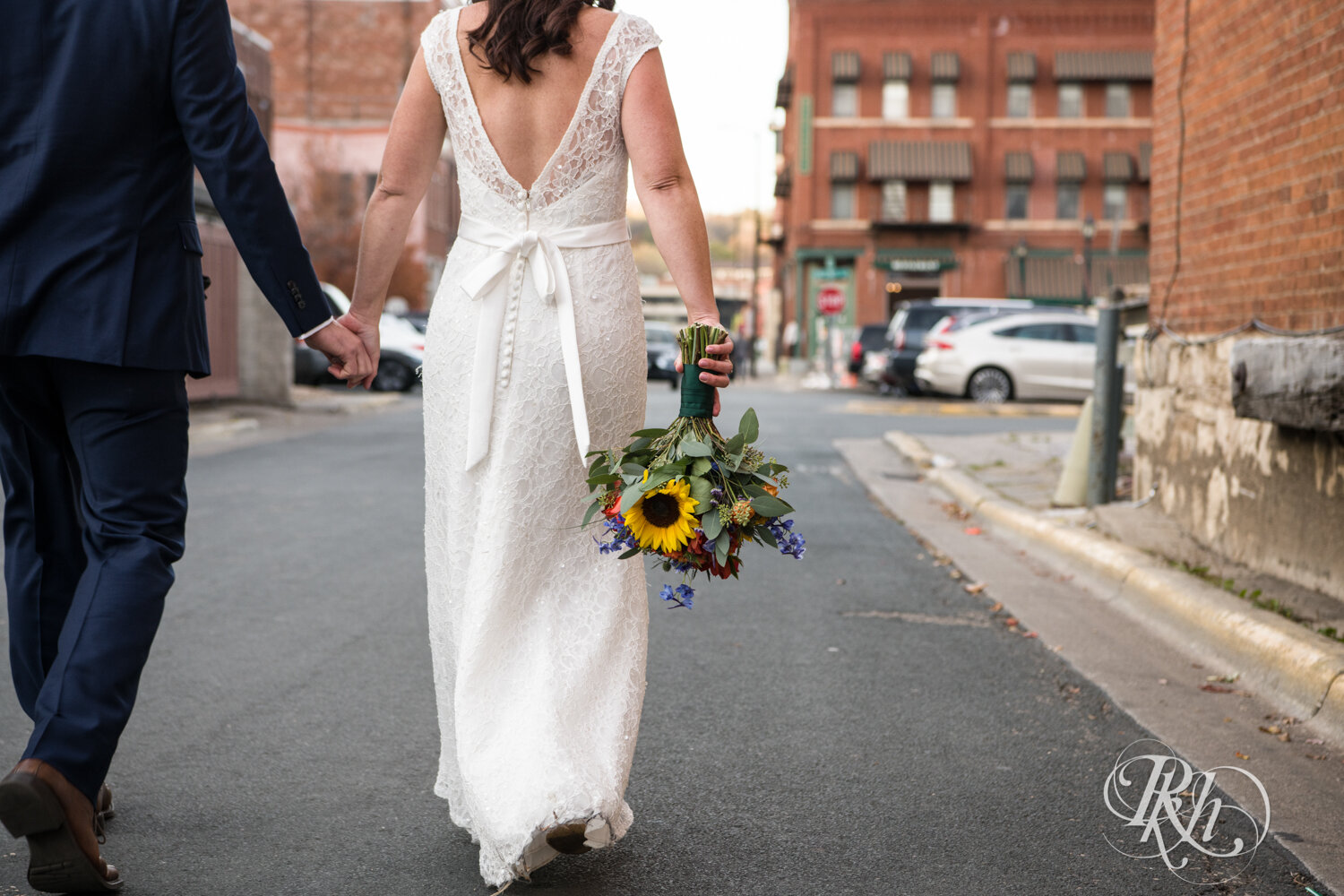 Bride and groom walk down city streets in Stillwater, Minnesota at sunset.