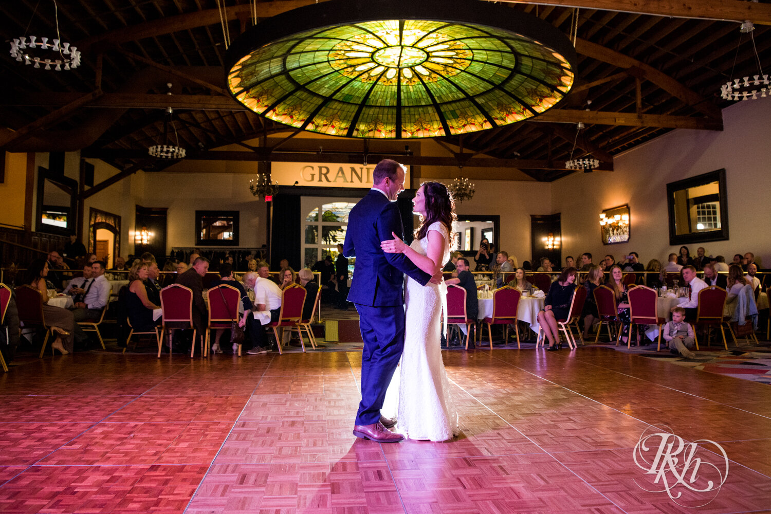 Bride and groom smile during first dance at Grand Banquet Hall in Stillwater, Minnesota.