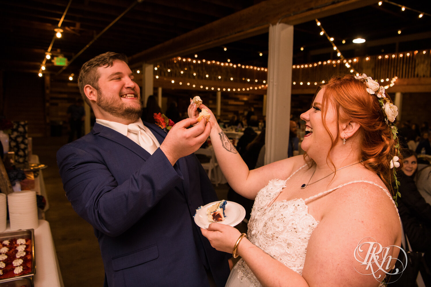 Plus size bride and groom eat cake at wedding reception at Olmsted County Fairgrounds in Rochester, Minnesota.