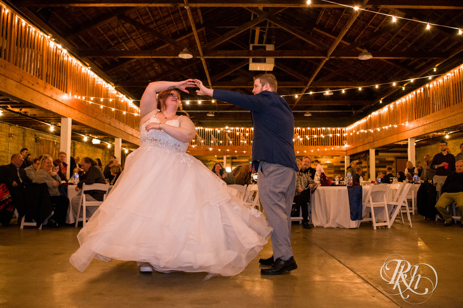Plus size bride and groom dance at wedding reception at Olmsted County Fairgrounds in Rochester, Minnesota.
