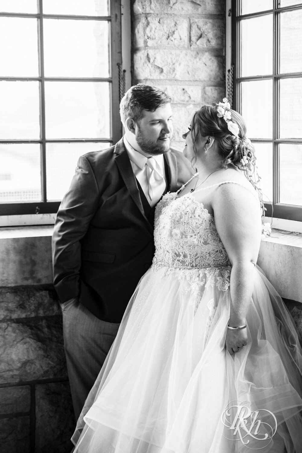 Plus size bride and groom stand by window at wedding at Olmsted County Fairgrounds in Rochester, Minnesota.
