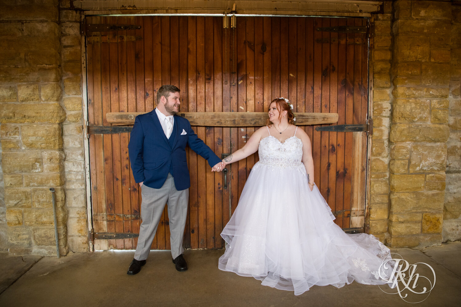 Plus size bride and groom hold hands at wedding at Olmsted County Fairgrounds in Rochester, Minnesota.