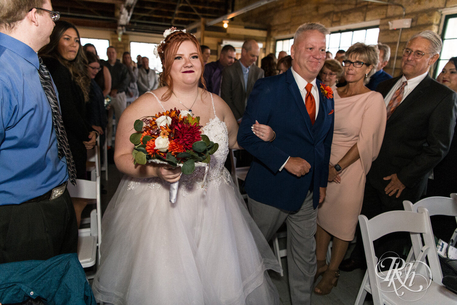 Plus size bride walks down aisle during wedding ceremony at Olmsted County Fairgrounds in Rochester, Minnesota.