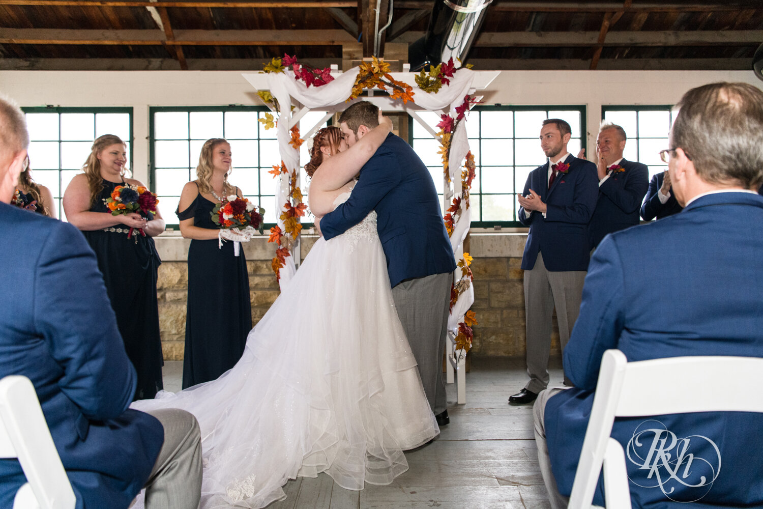 Plus size bride and groom kiss at wedding ceremony at Olmsted County Fairgrounds in Rochester, Minnesota.