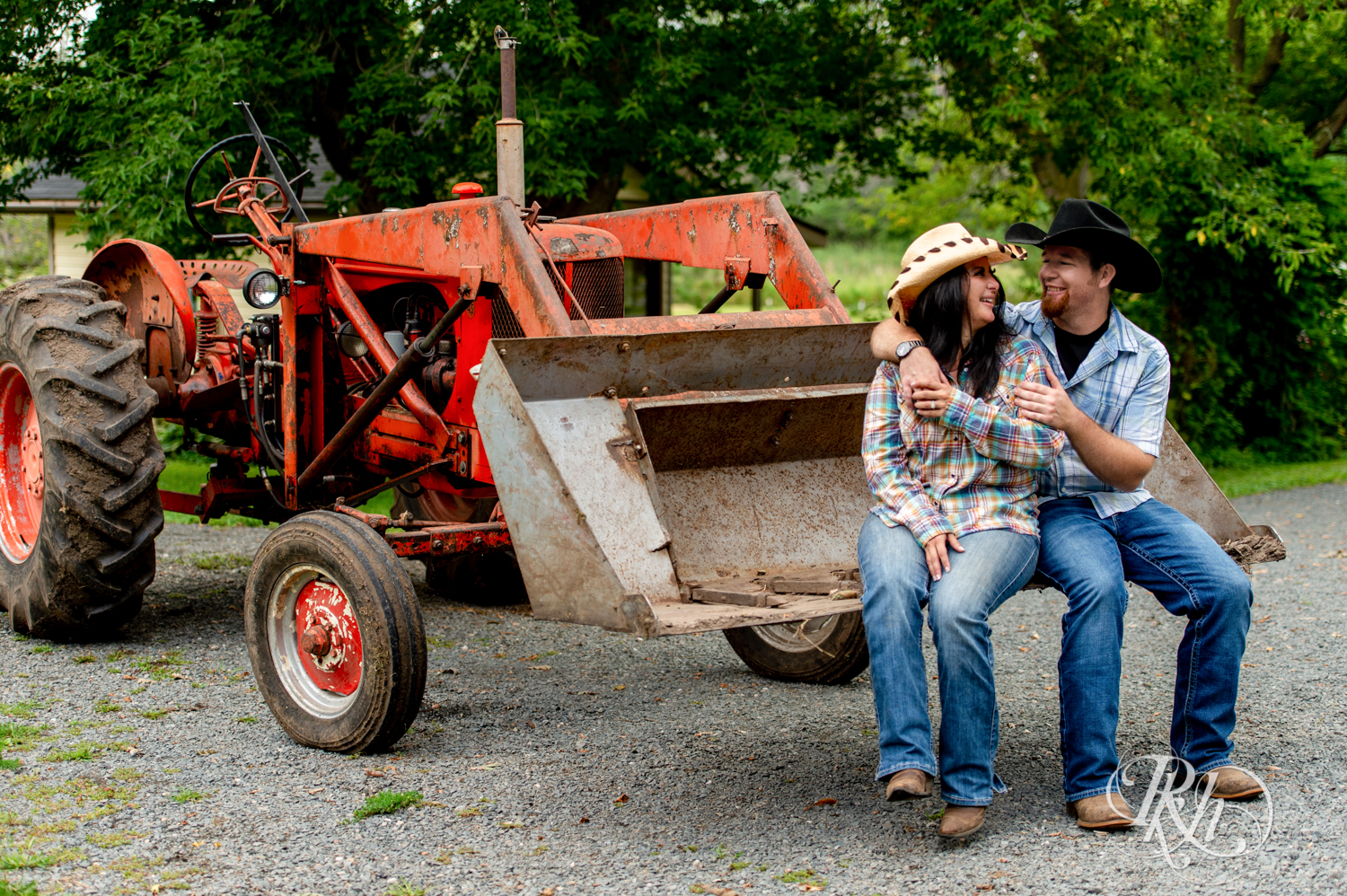 Lebanese woman and man in cowboy hats smile in tractor at their horse farm in Chisago City, Minnesota.