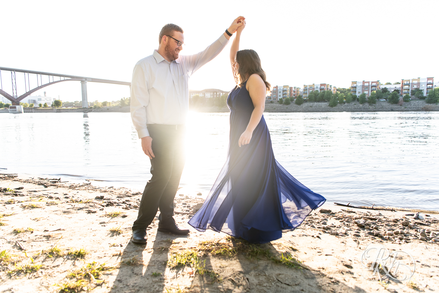Man in glasses and woman in blue dress dance during golden hour on Harriet Island in Saint Paul, Minnesota.