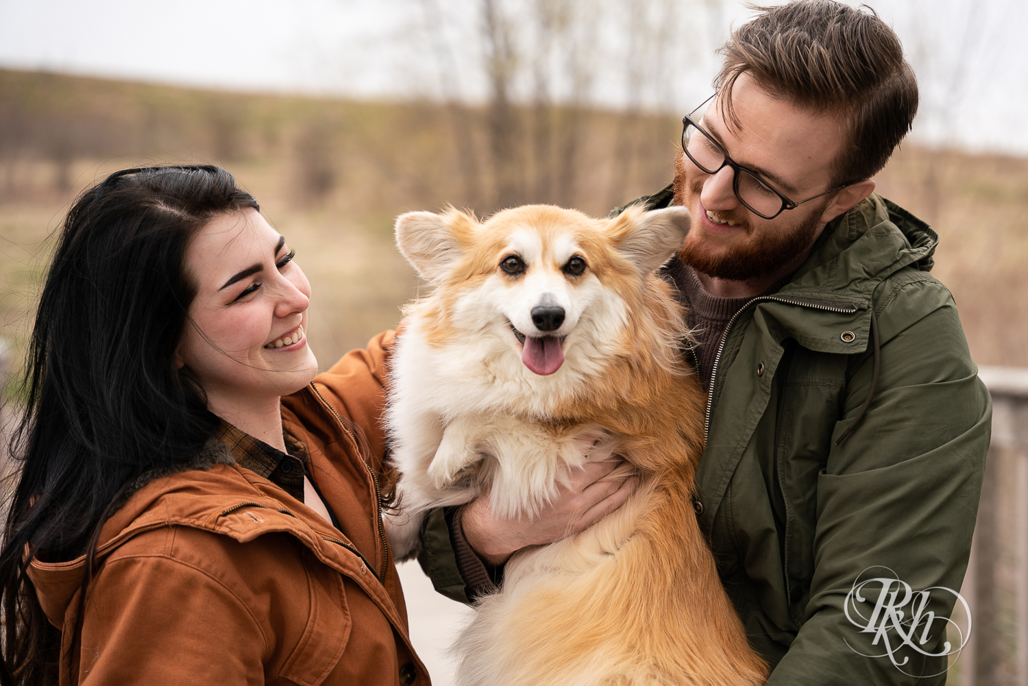 Man and woman in jackets hold Corgi dog at Lebanon Hills Regional Park in Eagan, Minnesota. 