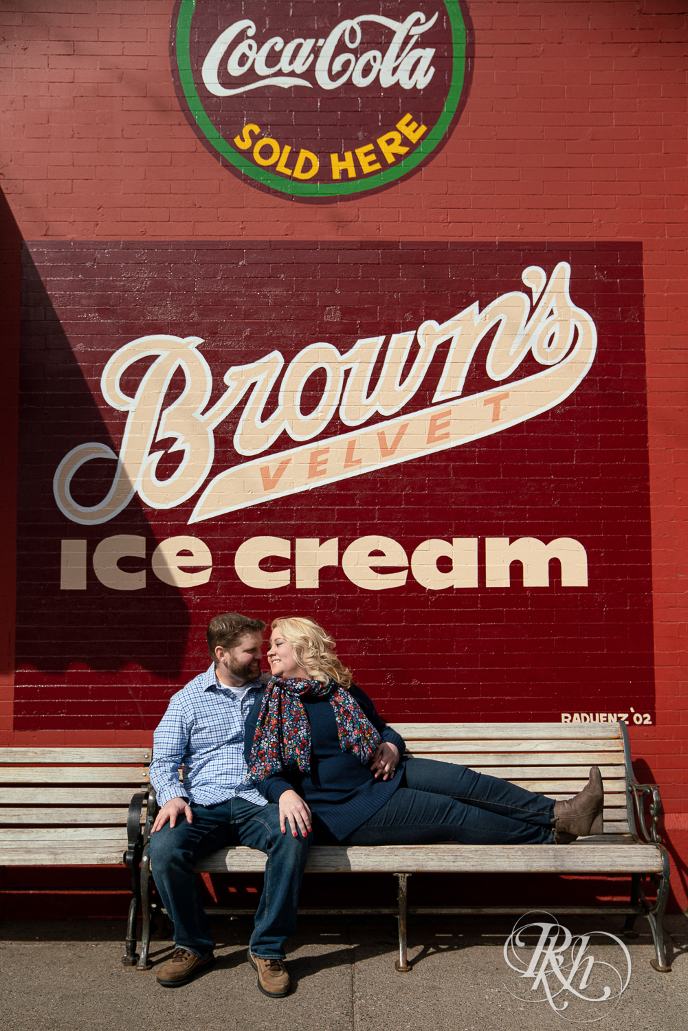 Blond woman and bearded man smile on bench in front of Brown's Velvet Ice Cream in Stillwater, Minnesota.