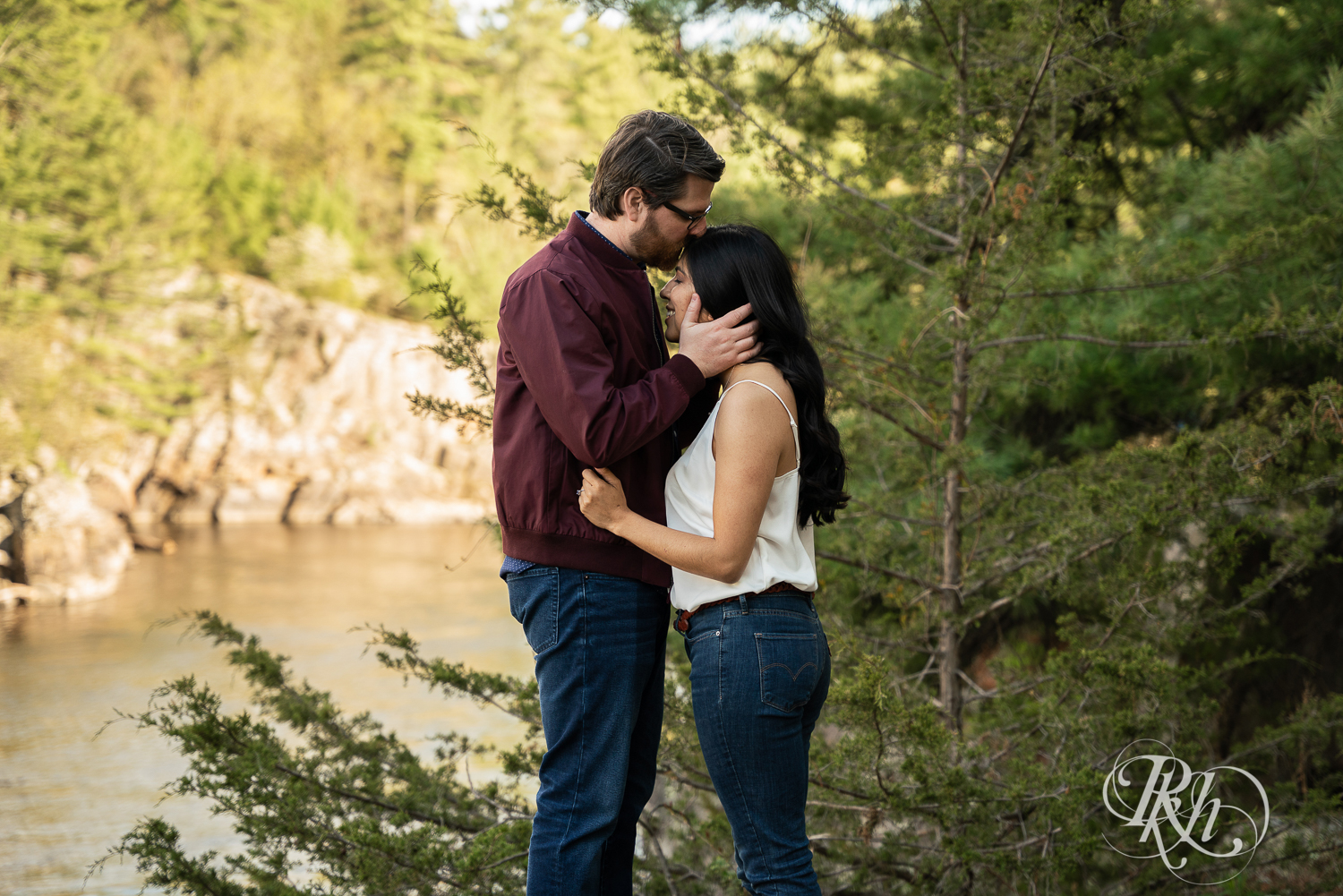 Man and woman in jeans kiss on cliff at Interstate State Park in Taylor's Fall, Minnesota.