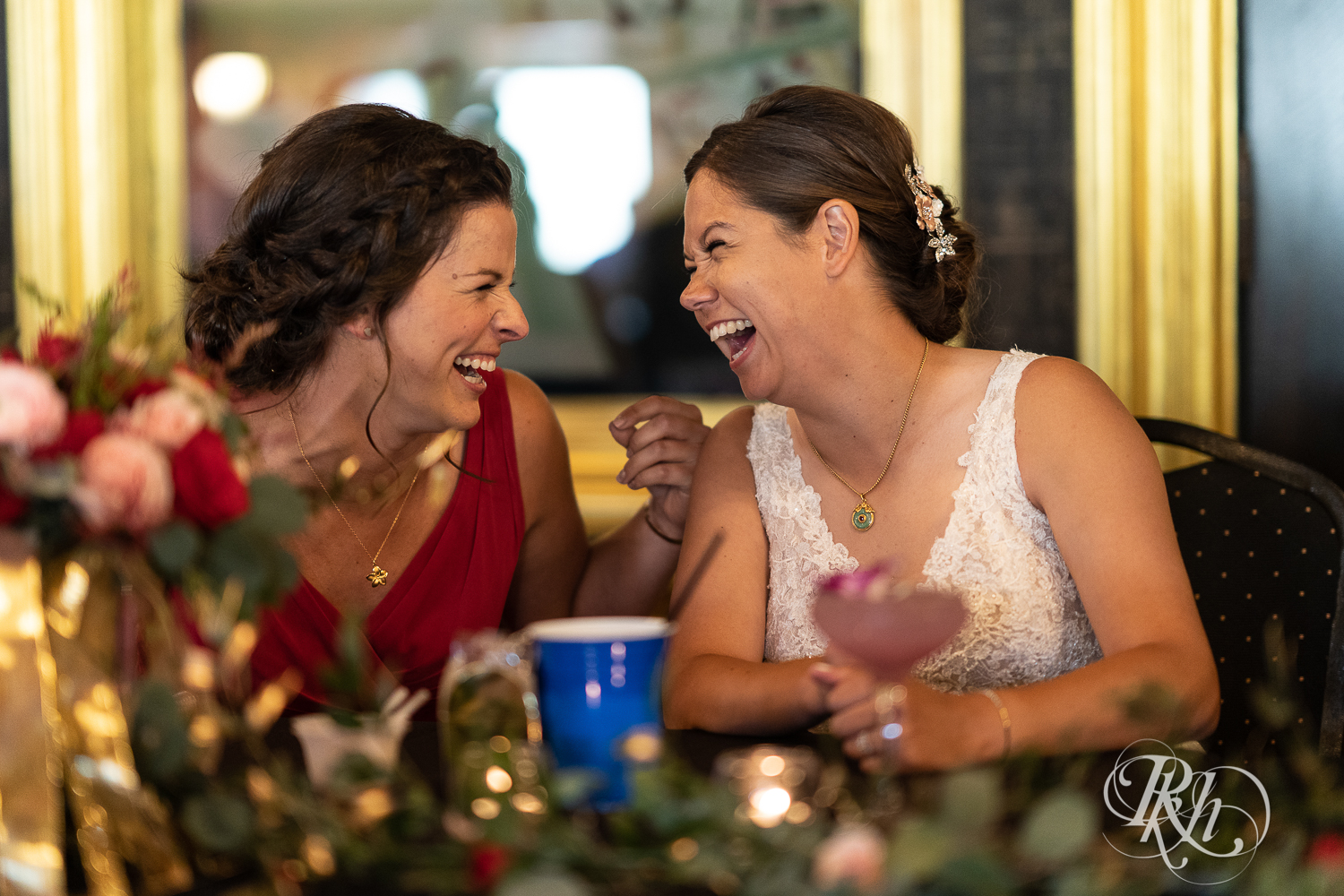Bride and bridesmaid laugh at wedding reception at Kellerman's Event Center in White Bear Lake, Minnesota.