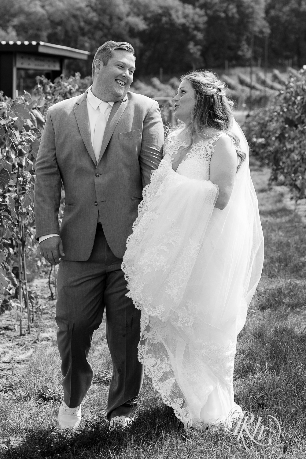 Bride and groom walking through vineyard at summer wedding at 7 Vines Vineyard in Dellwood, Minnesota.
