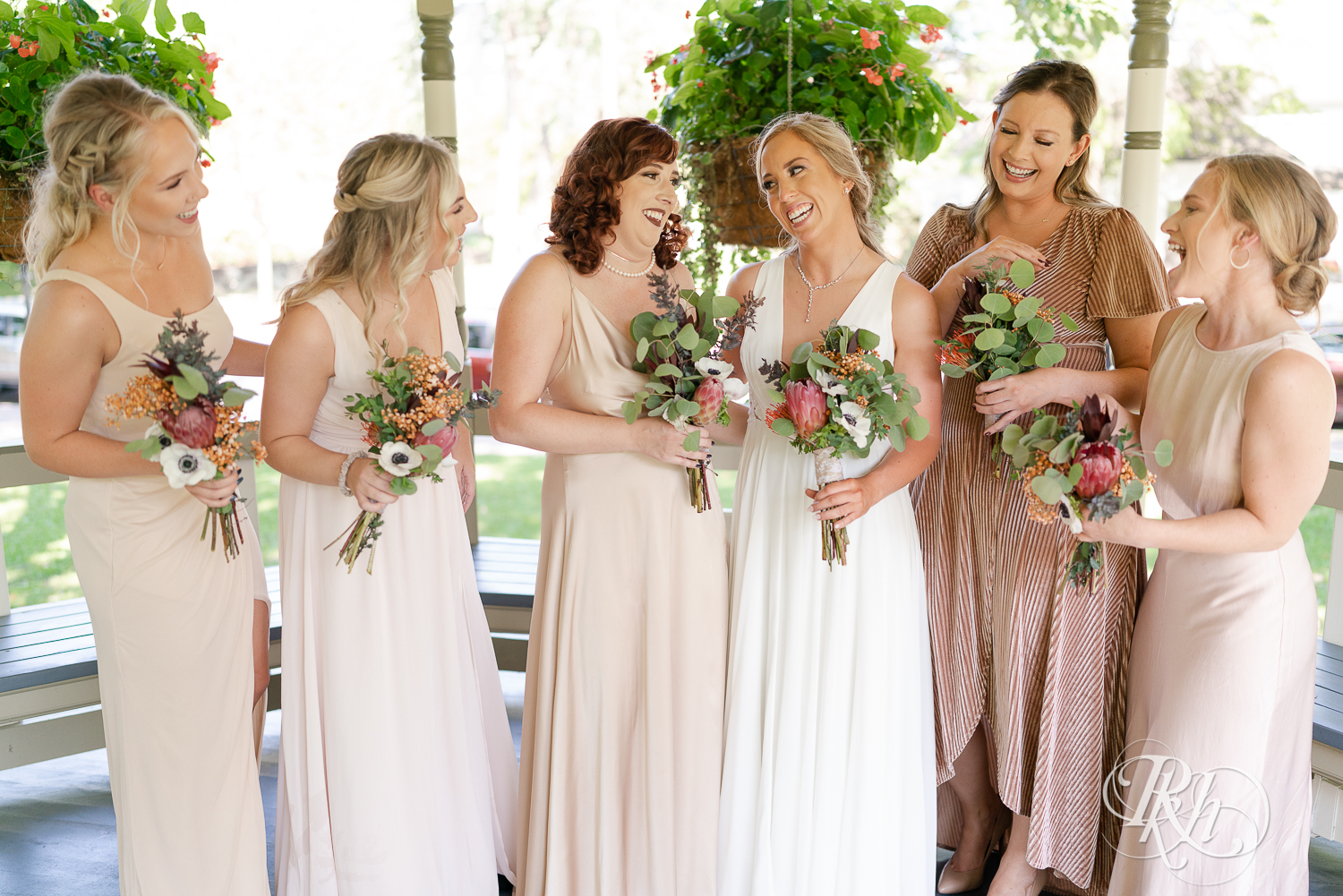 Wedding party in neutral color dresses smiling at Irvine Park in Saint Paul, Minnesota.