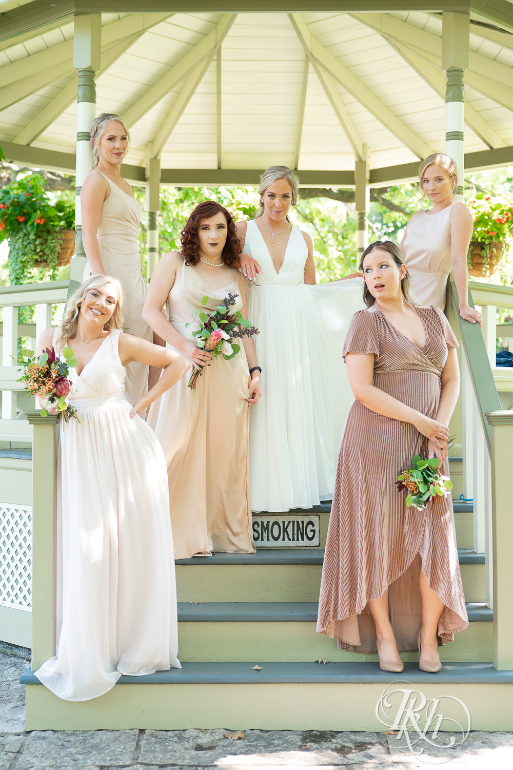Wedding party in neutral color dresses smiling at Irvine Park in Saint Paul, Minnesota.