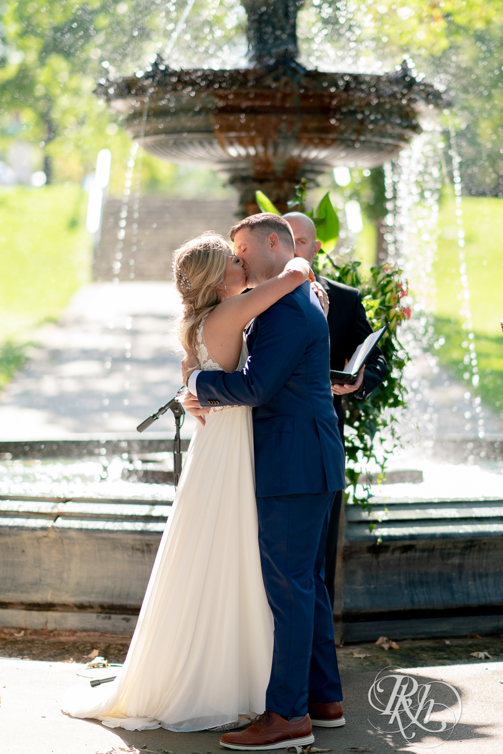 Bride and groom kiss in front of fountain at Irvine Park in Saint Paul, Minnesota.