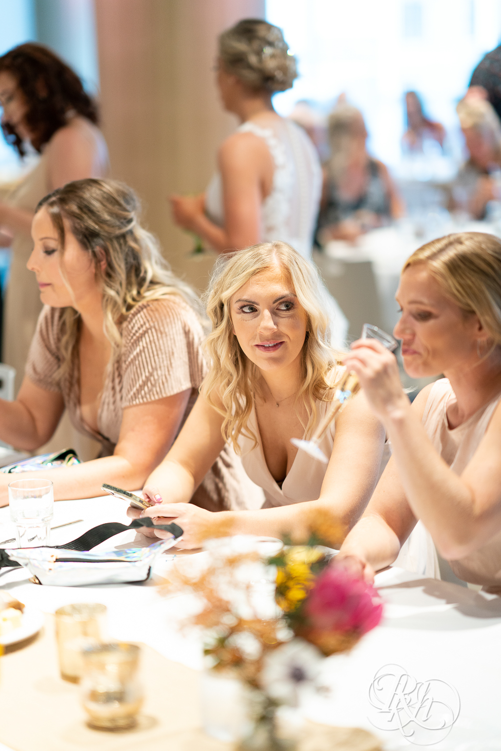 Bridesmaids converse during wedding reception at head table at Saint Paul Event Center in Saint Paul, Minnesota.