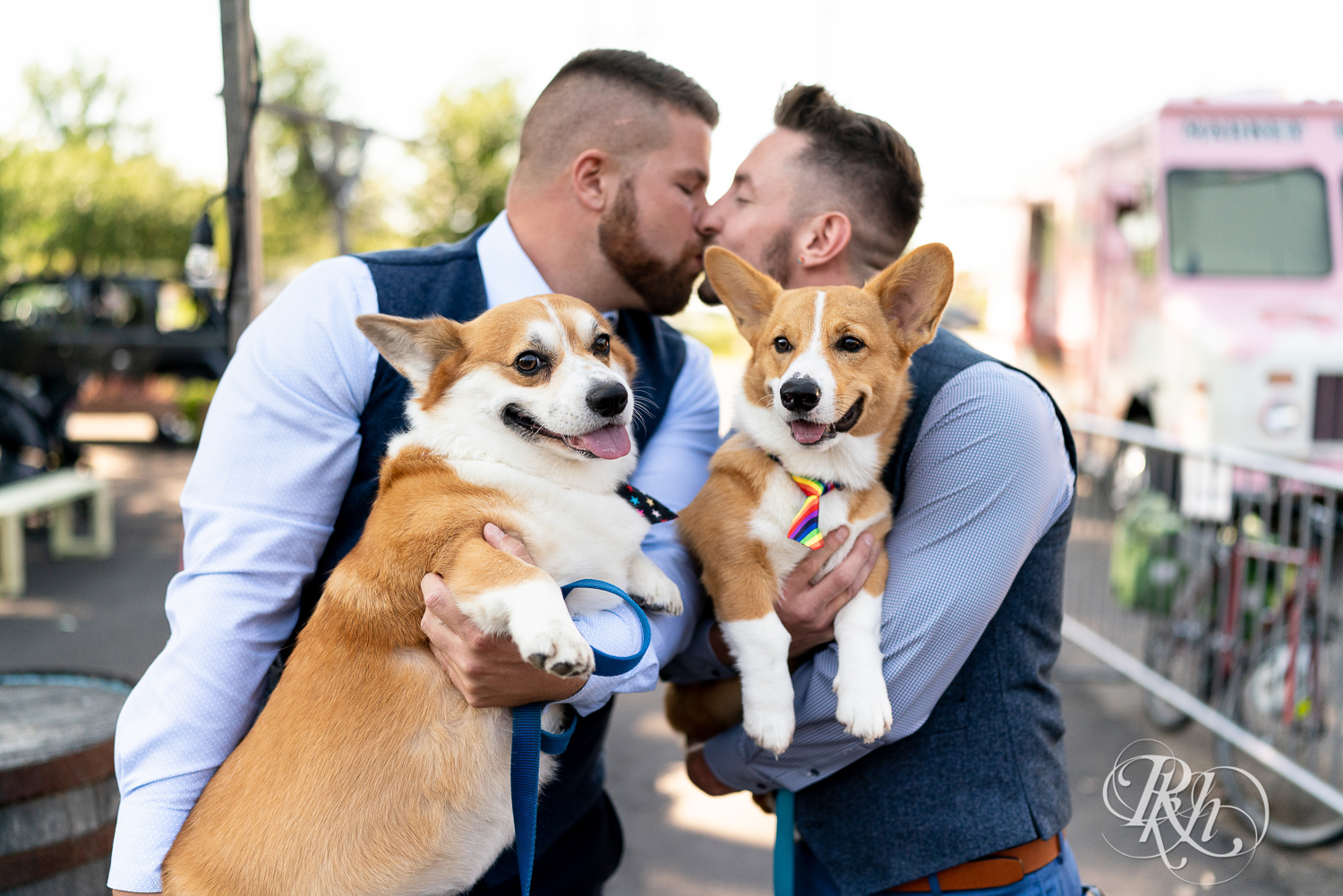 Gay grooms hugging Corgi puppy before wedding in Minneapolis, Minnesota while kissing in the background.
