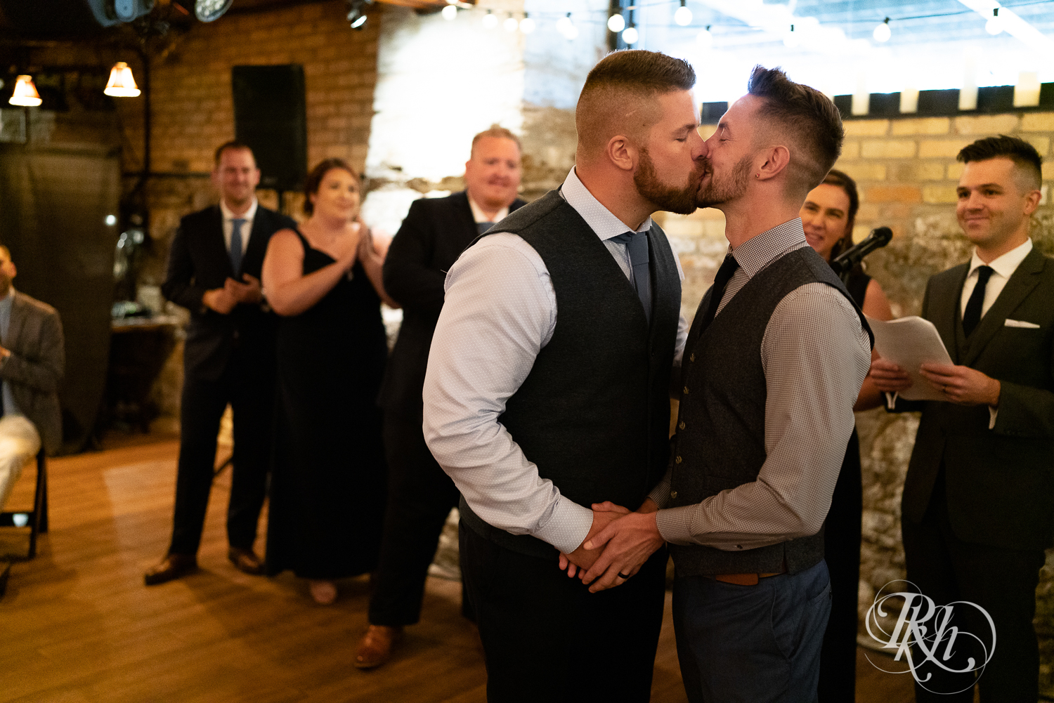 Gay grooms kiss at wedding alter on wedding day at Hall of Kings in Minneapolis, Minnesota.