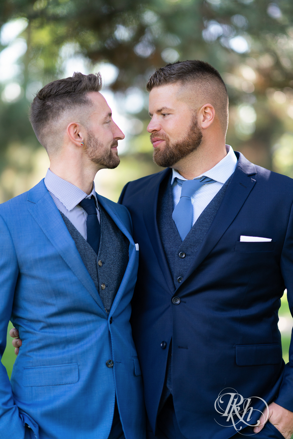 Gay grooms in blue suits smiling on wedding day at Nicollet Island in Minneapolis, Minnesota.