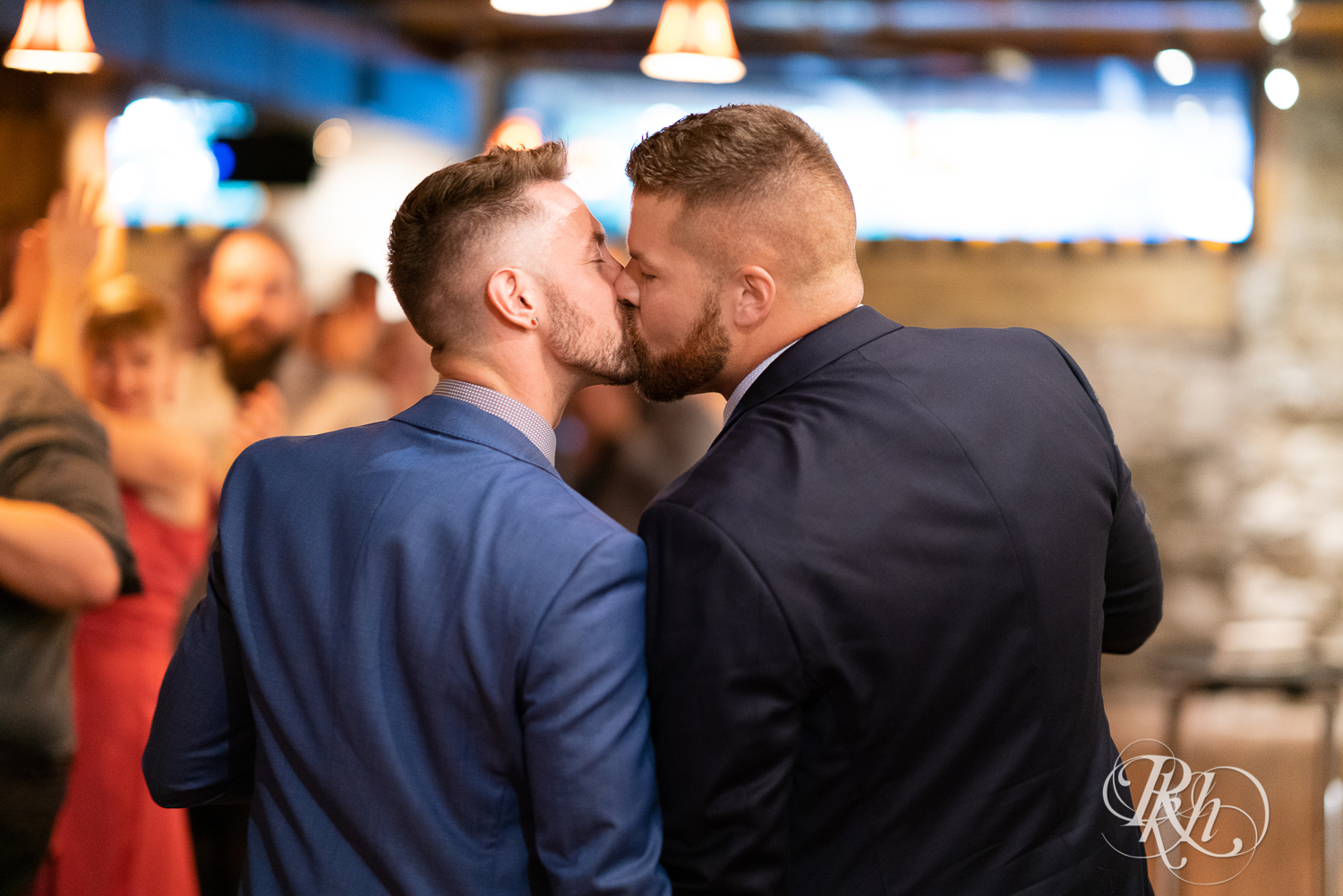 Gay grooms kissing during grand entrance on wedding day at Hall of Kings in Minneapolis, Minnesota.