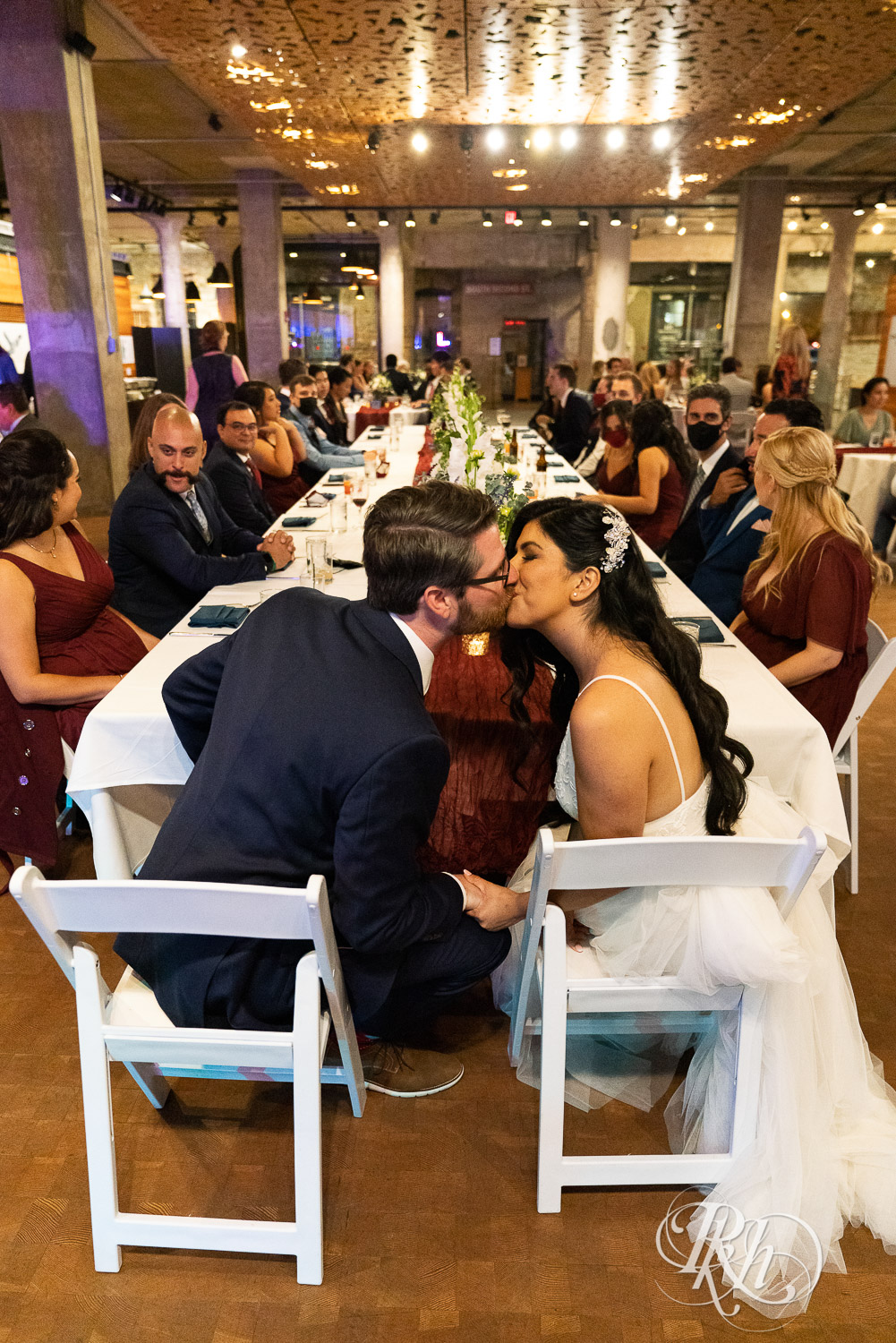 Bride and groom kissing at head table at wedding reception in Mill City Museum in Minneapolis, Minnesota.