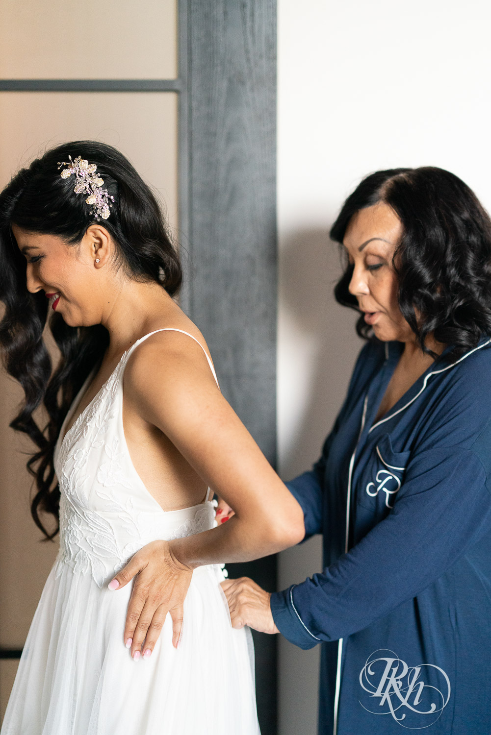 Mom buttoning bride into her wedding dress on her wedding day in Minneapolis, Minnesota.
