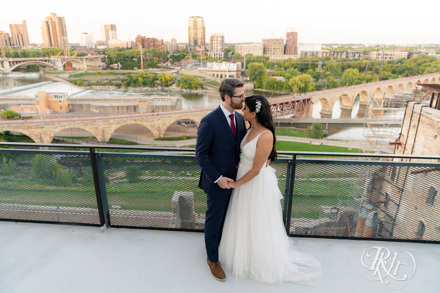 Bride and groom kissing on the roof of Mill City in Minneapolis, Minnesota with the skyline in the background.