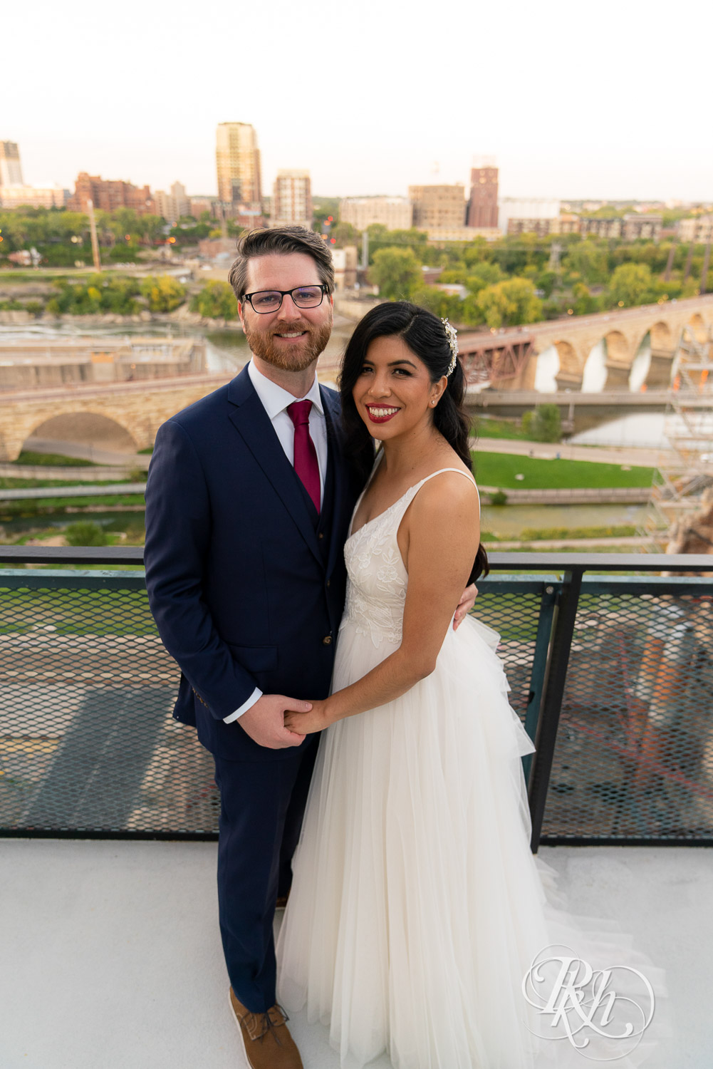 Bride and groom smiling on the roof of Mill City in Minneapolis, Minnesota with the skyline in the background.