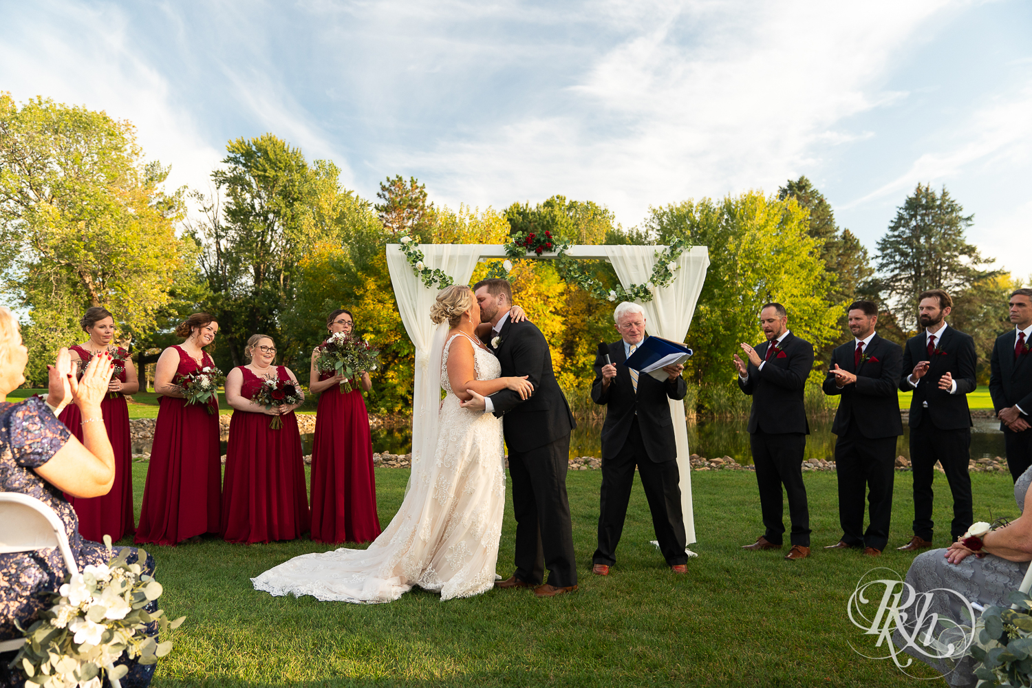 Bride and groom kiss at alter during outdoor wedding ceremony at Hastings Golf Club in Hastings, Minnesota.